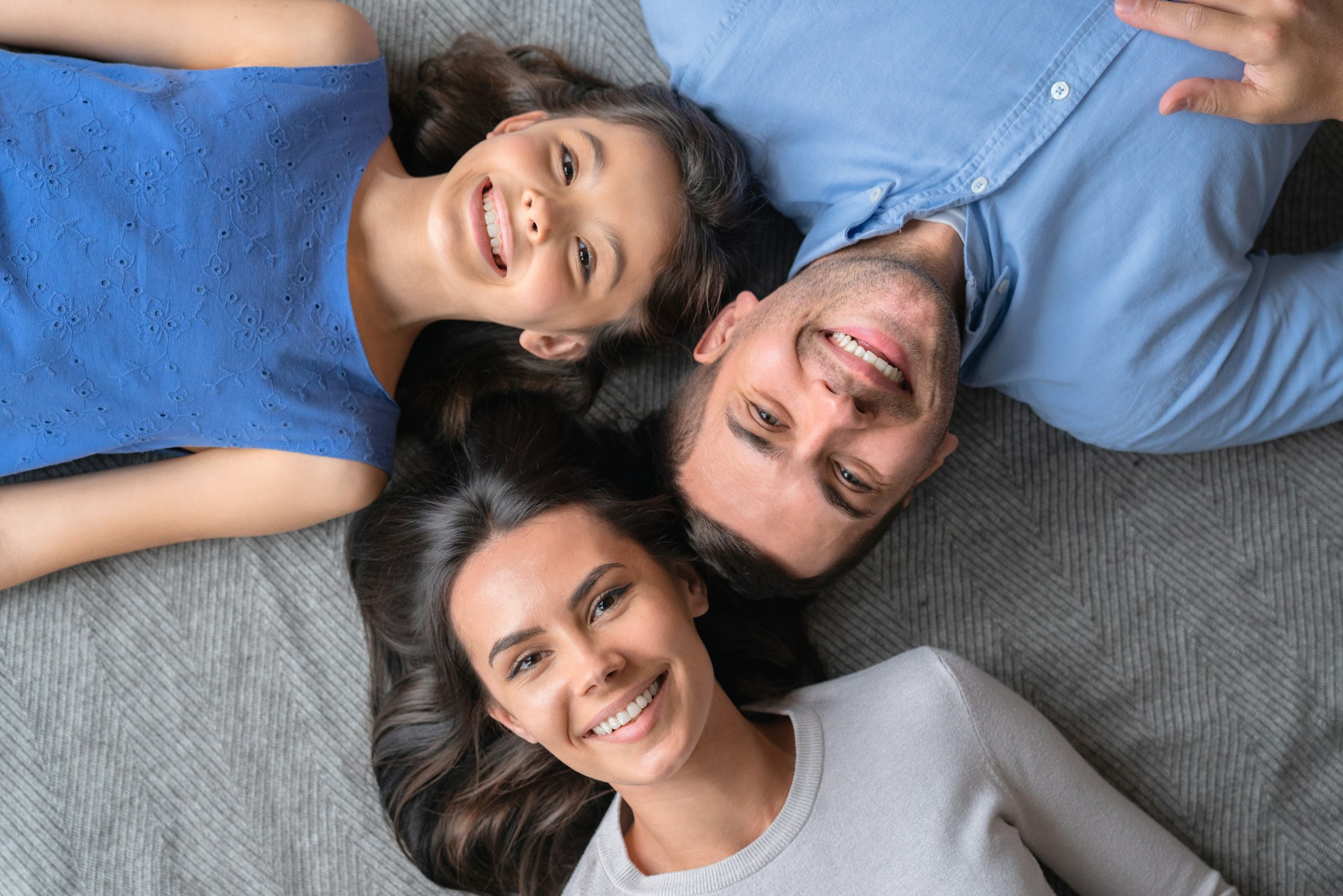 Happy family. Top view of happy family of three bonding to each other and smiling