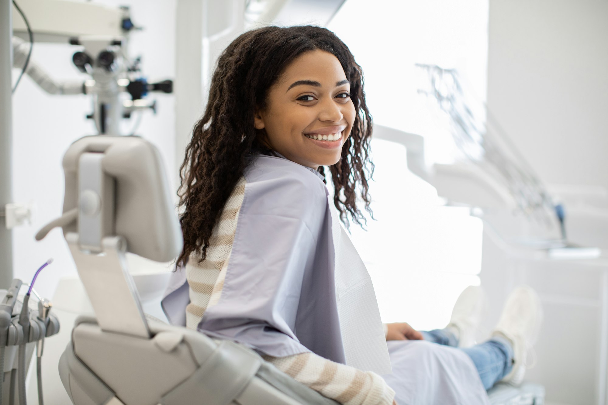 Happy Young Black Female Patient Sitting In Chair At Dental Clinic